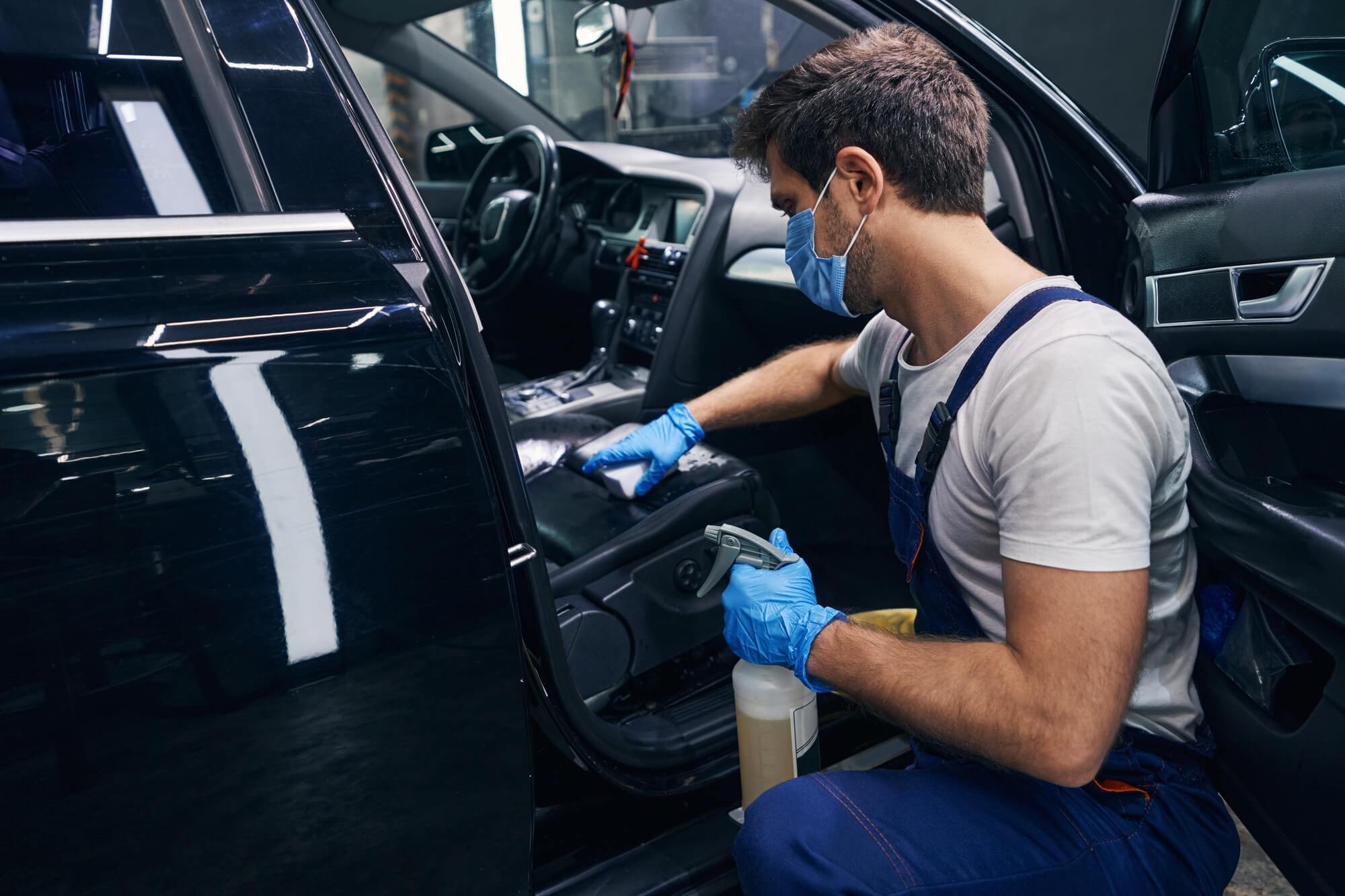 Professional detailer cleaning a vehicle interior in a shop